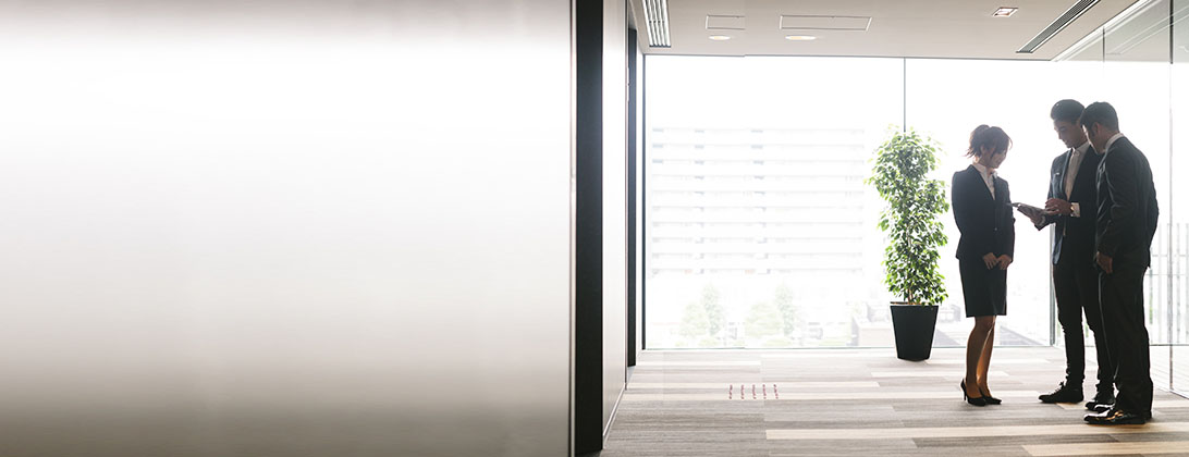 A group of 3 business people meet in a hallway to review documents