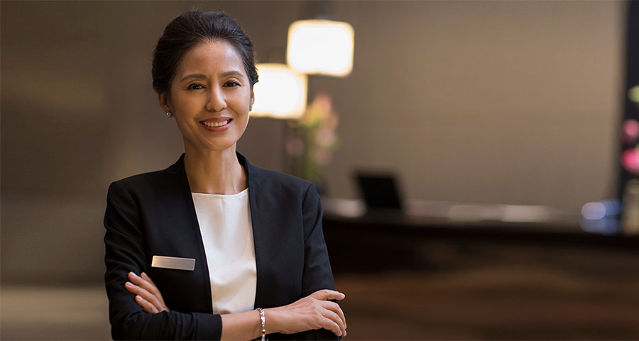 Woman in a blazer with arms crossed smiling at the camera