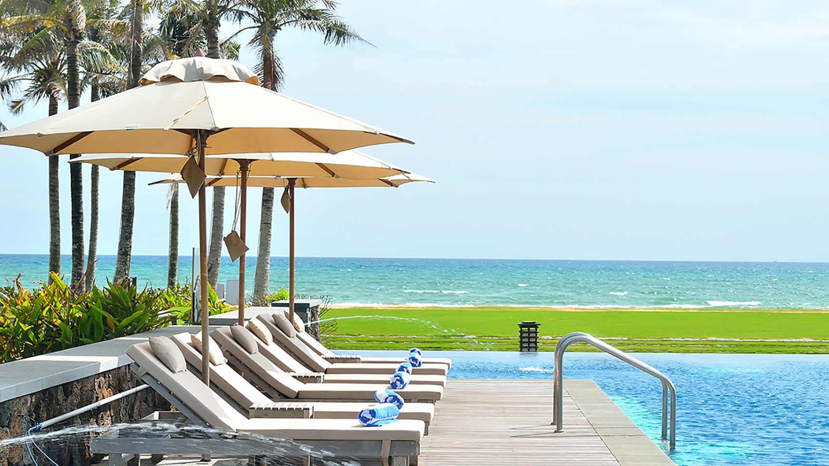 View of lounge chairs in the sun by an empty pool