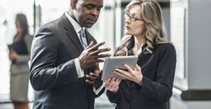 Two standing attorneys reviewing something on a tablet