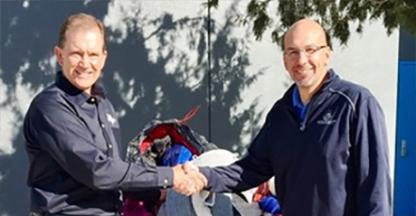 Two men shaking hands outside while looking at the camera