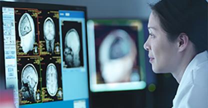 Doctor in a dark room reading an xray on a computer screen