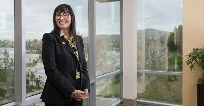 lady left of center in front of windows in office